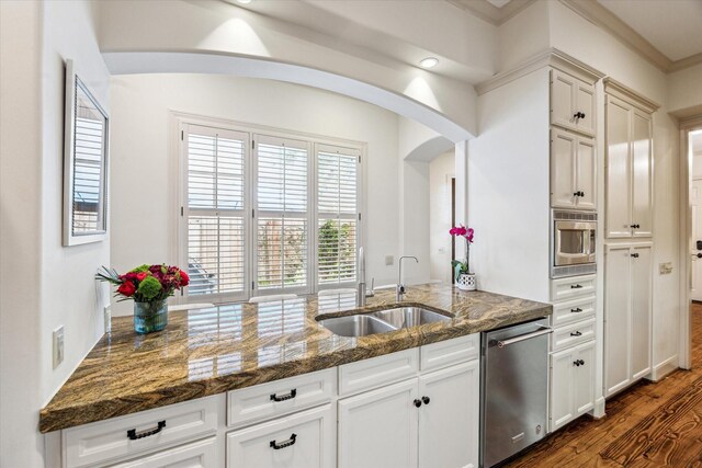 2207 Dunraven Ln, Houston, TX 77019 - kitchen with stainless steel appliances, dark wood-type flooring, white cabinetry, arched walkways, and dark stone counters