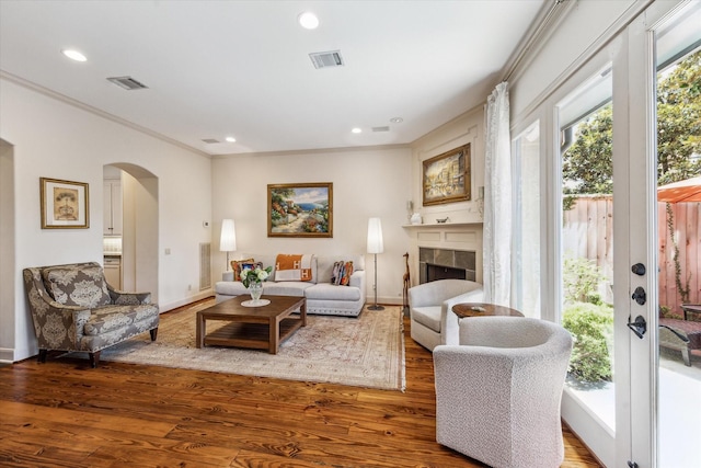 2207 Dunraven Ln, Houston, TX 77019 - living area with arched walkways, recessed lighting, wood finished floors, ornamental molding, and a tile fireplace