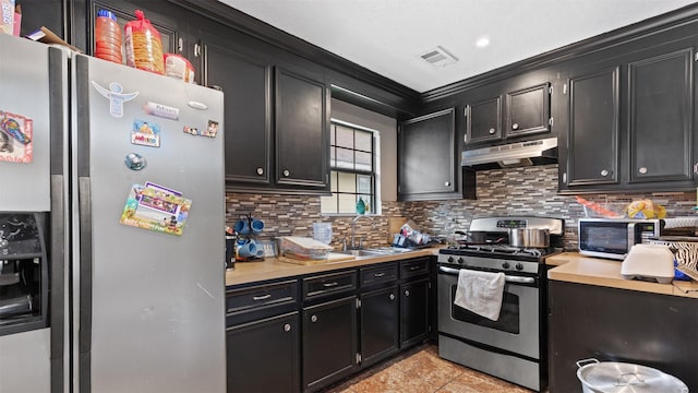 3409 Michigan St, Baytown, TX 77520 - kitchen with stainless steel appliances, under cabinet range hood, dark cabinets, tasteful backsplash, and ornamental molding