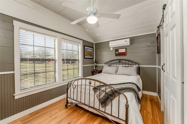 210 N Scott St, Fayetteville, TX 78940 - bedroom with an AC wall unit, lofted ceiling, hardwood / wood-style floors, wooden walls, and ceiling fan