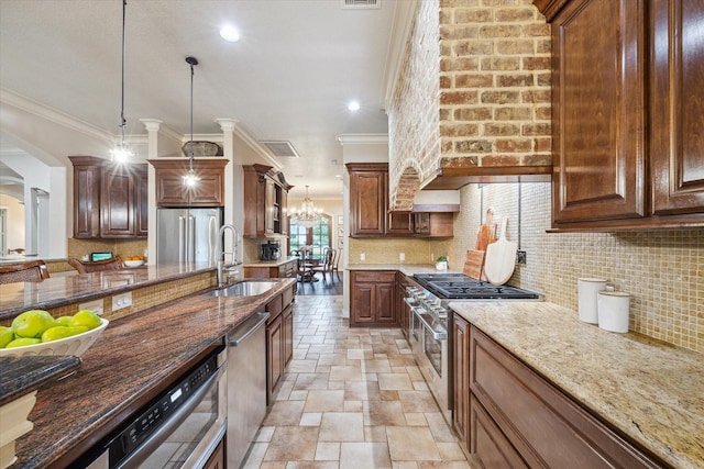1002 Cowards Creek Ct, Friendswood, TX 77546 - kitchen with stainless steel appliances, stone tile floors, crown molding, dark stone counters, and hanging light fixtures