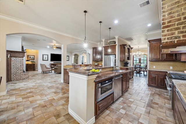1002 Cowards Creek Ct, Friendswood, TX 77546 - kitchen with stainless steel appliances, stone tile flooring, arched walkways, an island with sink, and crown molding