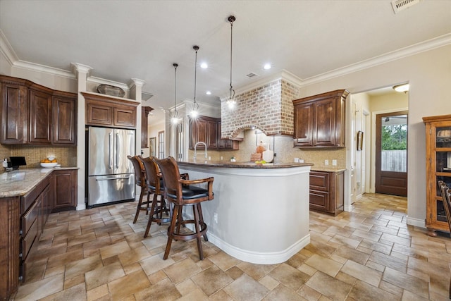 1002 Cowards Creek Ct, Friendswood, TX 77546 - kitchen with high end refrigerator, light stone finish flooring, decorative backsplash, ornamental molding, and a kitchen island with sink