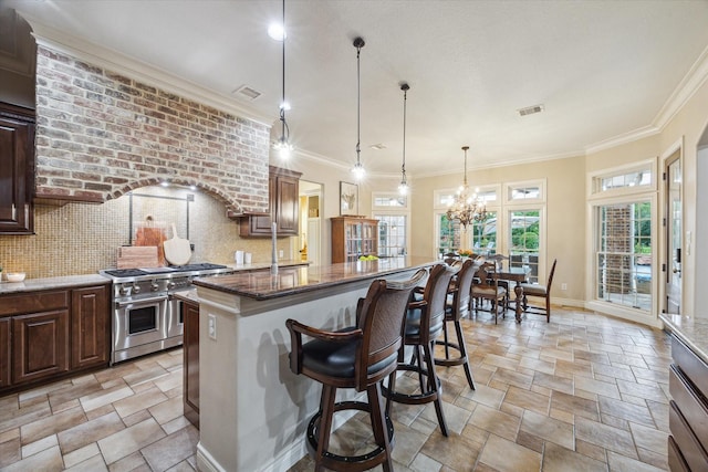 1002 Cowards Creek Ct, Friendswood, TX 77546 - kitchen with range with two ovens, stone tile flooring, a chandelier, dark stone counters, and a kitchen breakfast bar