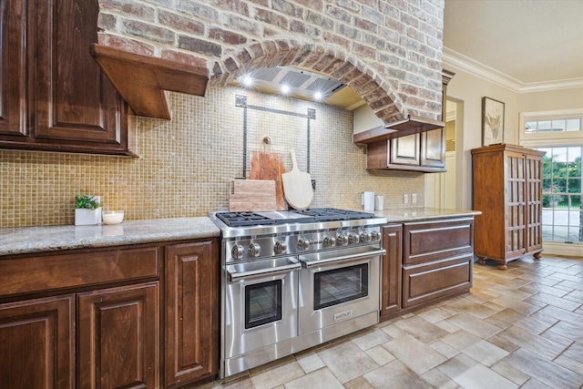 1002 Cowards Creek Ct, Friendswood, TX 77546 - kitchen with double oven range, backsplash, crown molding, light stone countertops, and dark brown cabinetry