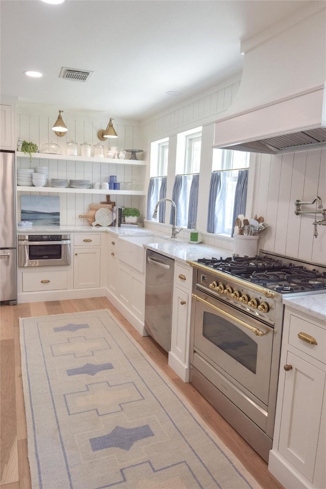 7611 Fairdale Ln, Houston, TX 77063 - kitchen featuring stainless steel appliances, custom exhaust hood, light wood-style flooring, white cabinetry, and open shelves