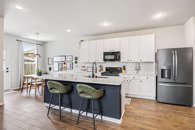 13110 Mid Stocket Dr, Humble, TX 77346 - kitchen featuring stainless steel fridge, black microwave, range, white cabinetry, and wood finished floors