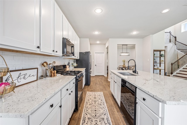 13110 Mid Stocket Dr, Humble, TX 77346 - kitchen featuring black appliances, light wood finished floors, white cabinets, a kitchen island with sink, and tasteful backsplash