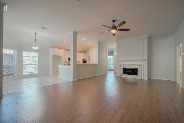 11607 Buck Springs Trl, Tomball, TX 77377 - unfurnished living room featuring a ceiling fan, light wood-style floors, a high end fireplace, decorative columns, and recessed lighting