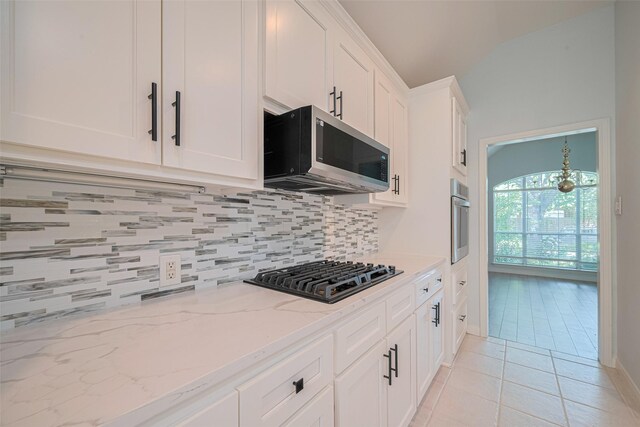 11607 Buck Springs Trl, Tomball, TX 77377 - kitchen with stainless steel appliances, tasteful backsplash, white cabinetry, light stone countertops, and lofted ceiling