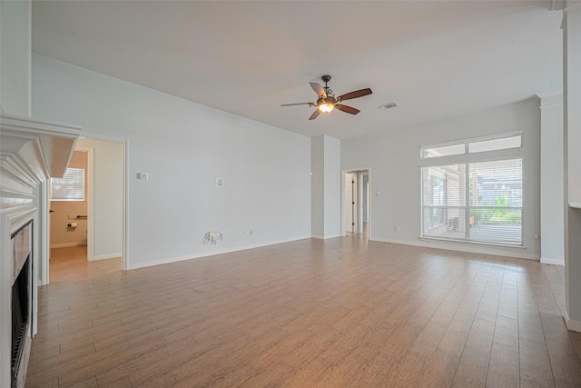 11607 Buck Springs Trl, Tomball, TX 77377 - unfurnished living room with a ceiling fan, a fireplace, and light wood finished floors