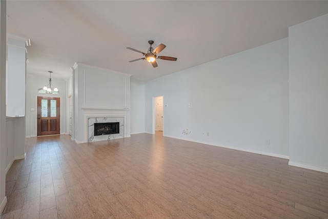 11607 Buck Springs Trl, Tomball, TX 77377 - unfurnished living room featuring light wood-type flooring, a chandelier, ceiling fan, and a high end fireplace