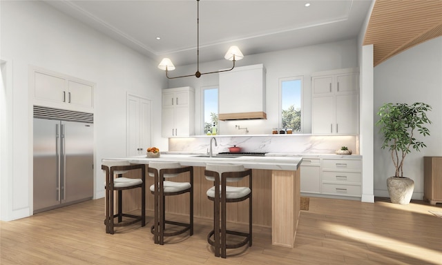 1002 E 25th St, Houston, TX 77009 - kitchen featuring built in refrigerator, a center island with sink, light wood finished floors, light countertops, and white cabinets