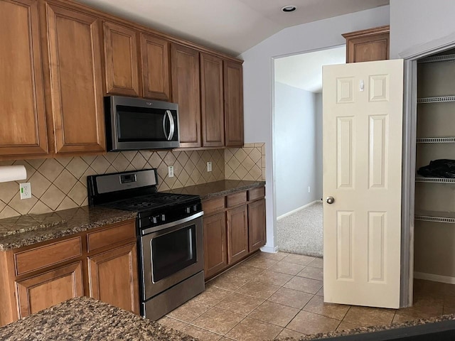 12610 Bethany Bay Dr, Pearland, TX 77584 - kitchen with stainless steel appliances, lofted ceiling, tasteful backsplash, and brown cabinets