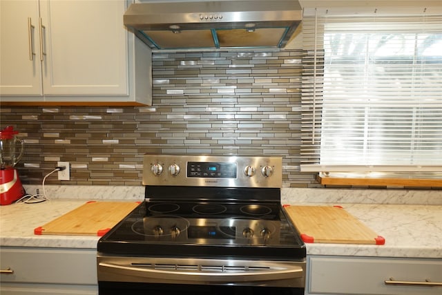 11822 Bandlon Dr, Houston, TX 77072 - kitchen with stainless steel range with electric stovetop, exhaust hood, backsplash, and white cabinetry