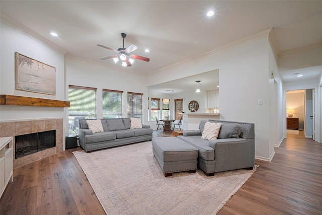 14311 Cally Cir, Needville, TX 77461 - living room featuring crown molding, a ceiling fan, wood finished floors, a tiled fireplace, and recessed lighting