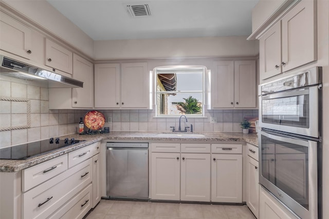 6415 Bayonne Dr, Spring, TX 77389 - kitchen featuring stainless steel appliances, under cabinet range hood, tasteful backsplash, and light stone countertops