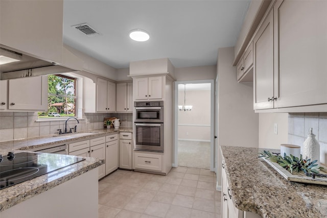 6415 Bayonne Dr, Spring, TX 77389 - kitchen with double oven, a chandelier, backsplash, light stone countertops, and black electric stovetop