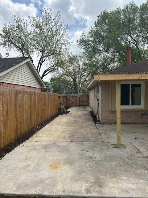 15834 Bazelbriar Ln, Houston, TX 77489 - view of side of property featuring a gate, brick siding, a patio area, and a chimney