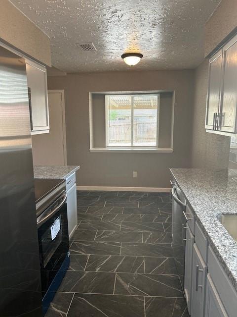 15834 Bazelbriar Ln, Houston, TX 77489 - kitchen featuring appliances with stainless steel finishes, a textured ceiling, and light stone counters