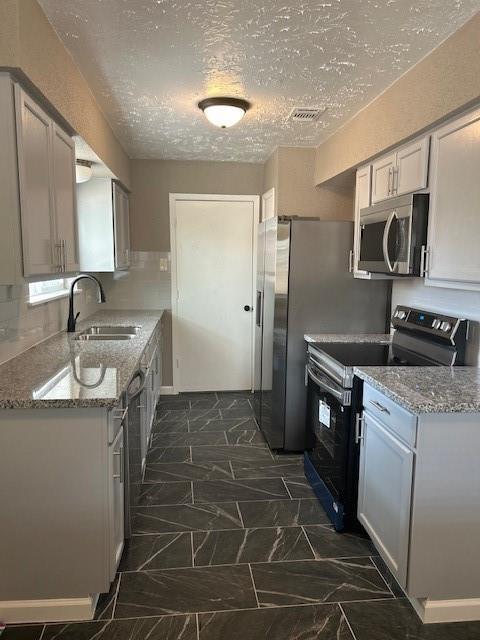 15834 Bazelbriar Ln, Houston, TX 77489 - kitchen with stainless steel microwave, electric range, light stone counters, a textured ceiling, and decorative backsplash