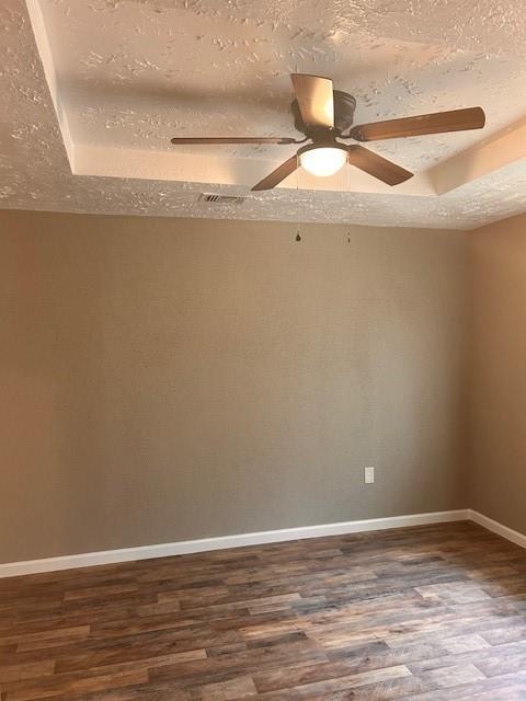 15834 Bazelbriar Ln, Houston, TX 77489 - spare room with dark wood finished floors, a textured ceiling, a ceiling fan, and a raised ceiling