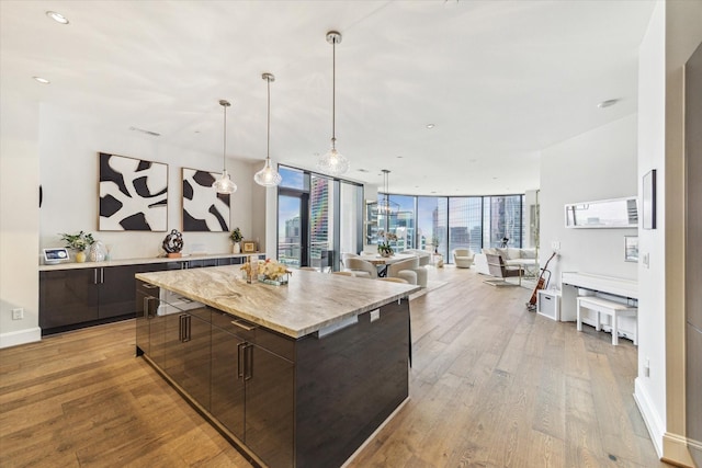 1409 Post Oak Blvd Unit 2204, Houston, TX 77056 - kitchen featuring dark brown cabinetry, modern cabinets, a kitchen island, light wood-type flooring, and expansive windows