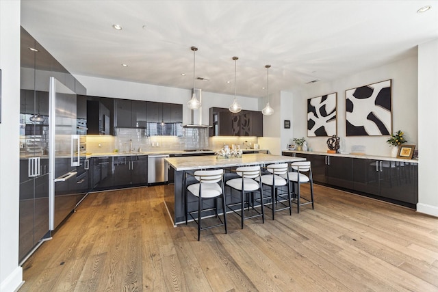 1409 Post Oak Blvd Unit 2204, Houston, TX 77056 - kitchen with stainless steel dishwasher, a kitchen island, light countertops, decorative backsplash, and a breakfast bar area