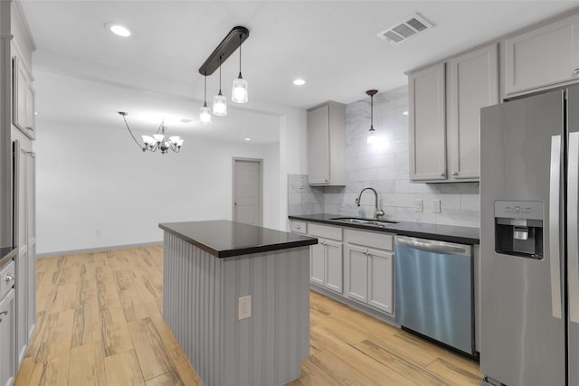 2934 Robertson St, Houston, TX 77009 - kitchen featuring appliances with stainless steel finishes, dark countertops, tasteful backsplash, a center island, and light wood-style floors