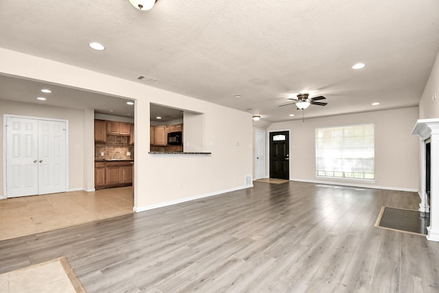 3502 Quail Meadow Dr, Missouri City, TX 77459 - unfurnished living room featuring a ceiling fan, recessed lighting, light wood-style floors, a fireplace, and a textured ceiling