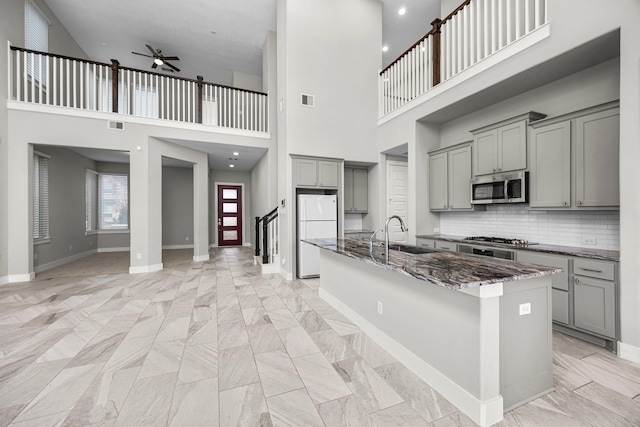 13207 Terania Cliff Trce, Houston, TX 77059 - kitchen featuring gray cabinets, appliances with stainless steel finishes, a ceiling fan, dark stone countertops, and an island with sink