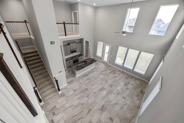 13207 Terania Cliff Trce, Houston, TX 77059 - unfurnished living room with ceiling fan, a towering ceiling, and stairs