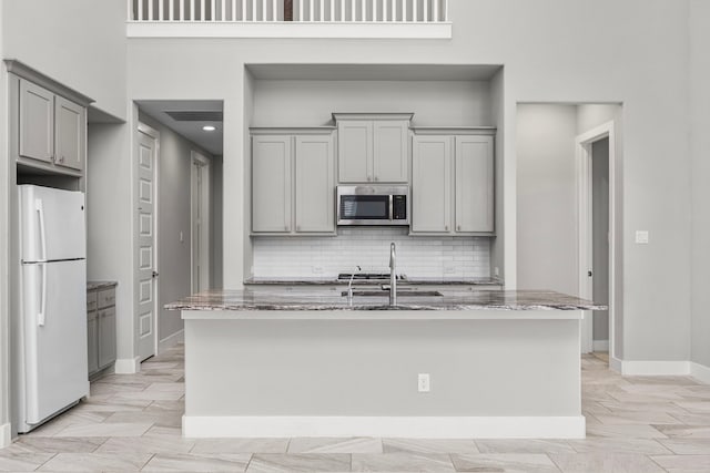 13207 Terania Cliff Trce, Houston, TX 77059 - kitchen featuring freestanding refrigerator, stainless steel microwave, gray cabinetry, and light stone counters