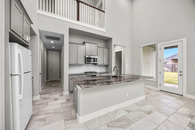 13207 Terania Cliff Trce, Houston, TX 77059 - kitchen with stainless steel appliances, gray cabinets, light marble finish flooring, dark stone counters, and a towering ceiling