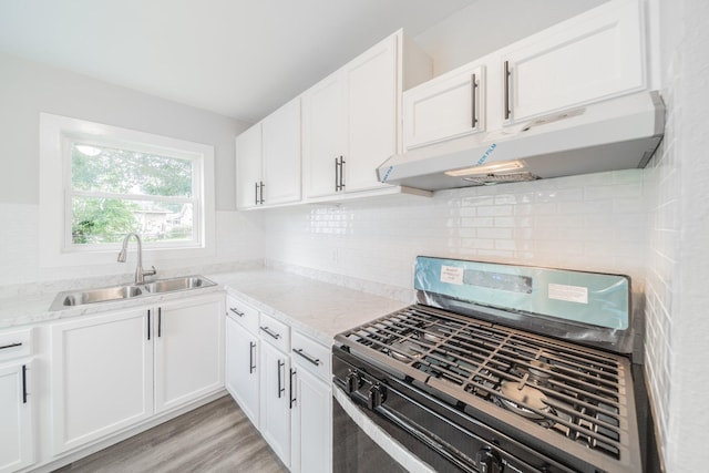 6307 Westover St, Houston, TX 77087 - kitchen with range with gas stovetop, under cabinet range hood, white cabinets, backsplash, and light wood-style flooring