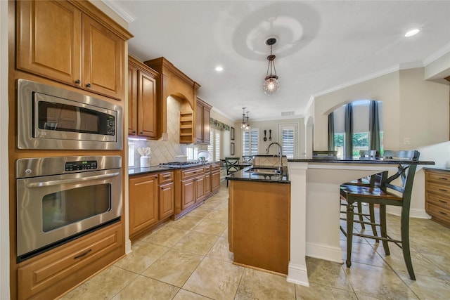 5714 Spring River Ln, Fulshear, TX 77441 - kitchen with stainless steel appliances, crown molding, brown cabinets, tasteful backsplash, and a center island with sink