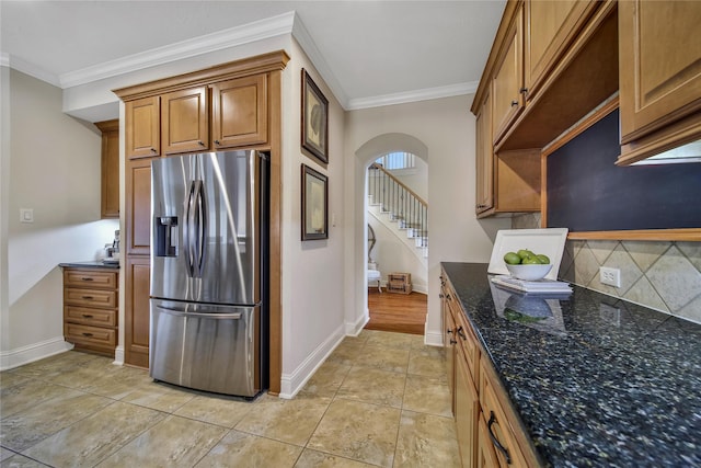 5714 Spring River Ln, Fulshear, TX 77441 - kitchen with stainless steel fridge, arched walkways, crown molding, backsplash, and brown cabinetry