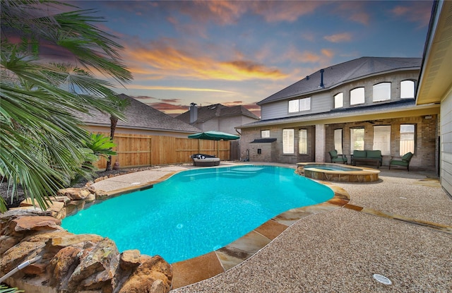 5714 Spring River Ln, Fulshear, TX 77441 - pool at dusk with a patio, a pool with connected hot tub, and a fenced backyard