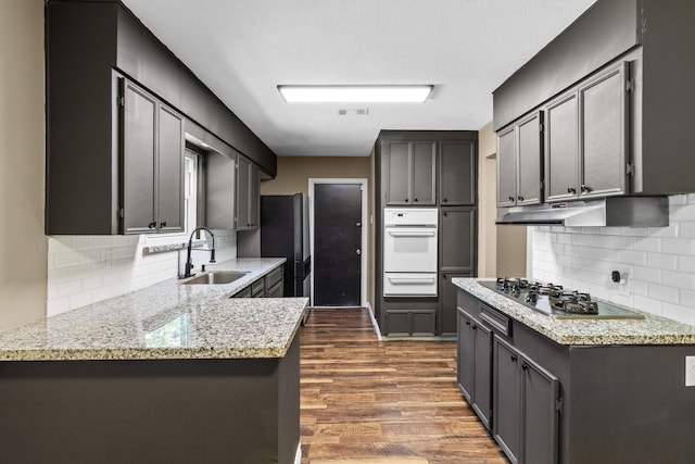 109 Timber Ln, Baytown, TX 77520 - kitchen with appliances with stainless steel finishes, a warming drawer, dark wood-style flooring, a peninsula, and tasteful backsplash
