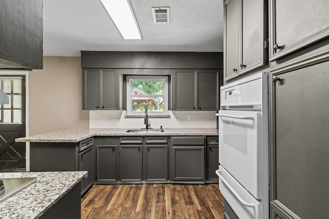 109 Timber Ln, Baytown, TX 77520 - kitchen featuring a warming drawer, gray cabinets, white oven, decorative backsplash, and dark wood finished floors