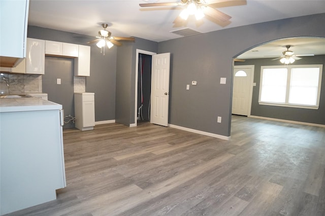 6803 6th St, Hitchcock, TX 77563 - kitchen featuring ceiling fan, white cabinetry, tasteful backsplash, arched walkways, and light wood finished floors