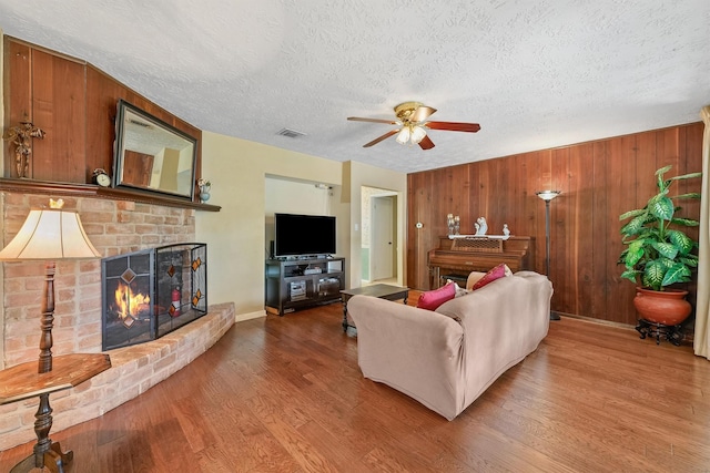 11815 Sharpview Dr, Houston, TX 77072 - living area featuring a textured ceiling, a fireplace, wood finished floors, ceiling fan, and wood walls