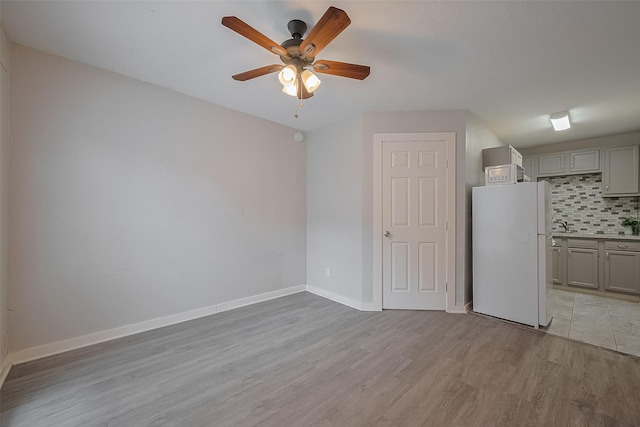 1813 Hatwell St, Houston, TX 77023 - kitchen with freestanding refrigerator, gray cabinets, ceiling fan, backsplash, and light wood-type flooring