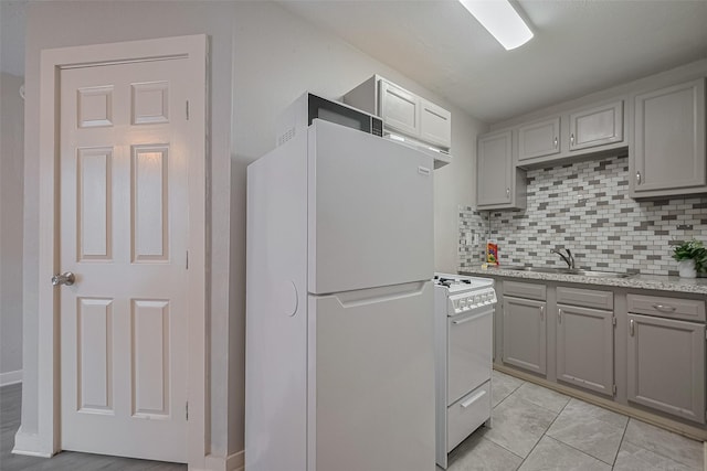 1813 Hatwell St, Houston, TX 77023 - kitchen with white appliances, gray cabinetry, backsplash, and light stone counters