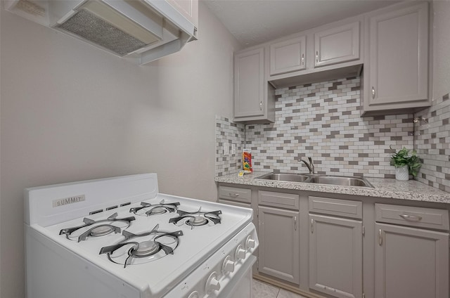 1813 Hatwell St, Houston, TX 77023 - kitchen with white gas range oven, range hood, gray cabinetry, and backsplash