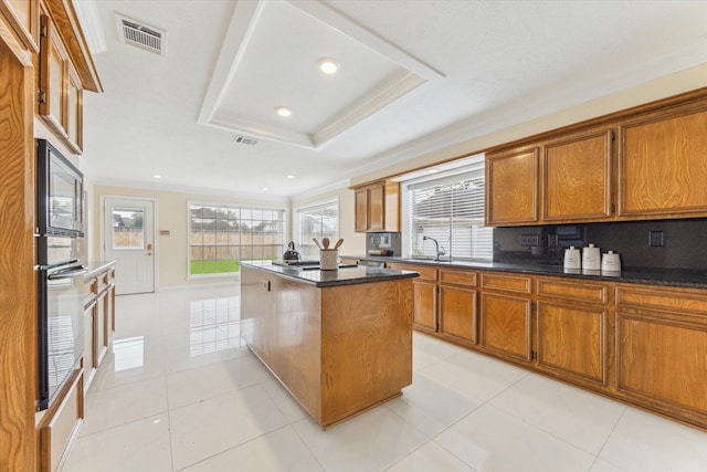 2125 Tipperary Dr, Pearland, TX 77581 - kitchen with brown cabinets, black appliances, a kitchen island, ornamental molding, and light tile patterned floors