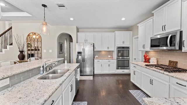 14926 Kenton Place Ln, Cypress, TX 77429 - kitchen with appliances with stainless steel finishes, dark wood-style floors, backsplash, arched walkways, and white cabinets