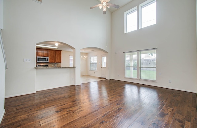 11610 Cross Spring Dr, Pearland, TX 77584 - unfurnished living room with a ceiling fan, a towering ceiling, dark wood finished floors, a chandelier, and arched walkways