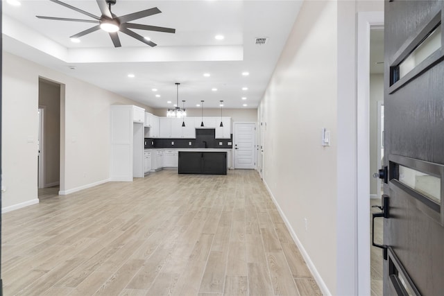 4120 S Kemp Ave, Edinburg, TX 78542 - unfurnished living room featuring a ceiling fan, light wood-style floors, a raised ceiling, recessed lighting, and a chandelier