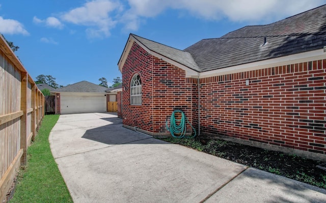 16214 Lobo Ln, Spring, TX 77379 - view of home's exterior with brick siding, roof with shingles, an outdoor structure, and a garage